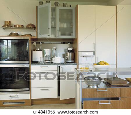 Electric appliances on worktop below glazed cupboard in modern white kitchen with double oven and concealed fridge View Large Photo Image Stock Photography - Electric appliances on worktop below glazed cupboard in modern white kitchen with double oven and concealed fridge. Fotosearch