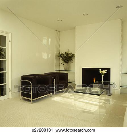Stock Image - Fireplace and black armchairs in modern white living room. Fotosearch