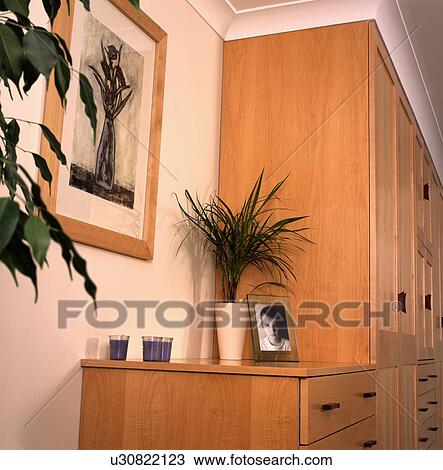 Stock Image - Fitted pine wardrobe and chest of drawers in bedroom with black+white print on the wall. Fotosearch
