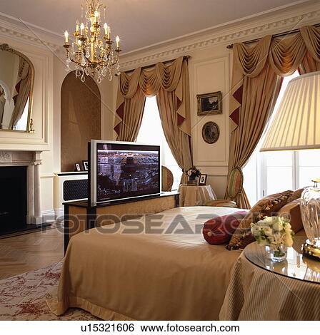 Flatscreen television concealed in chest below bed in opulent bedroom with antique glass chandelier View Large Photo Image Stock Photograph - Flatscreen television concealed in chest below bed in opulent bedroom with antique glass chandelier. Fotosearch