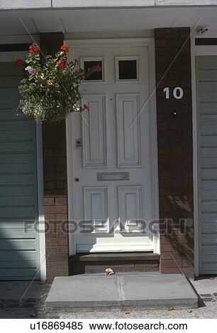 Stock Photography - Flowering plants in hanging basket beside white front door. Fotosearch