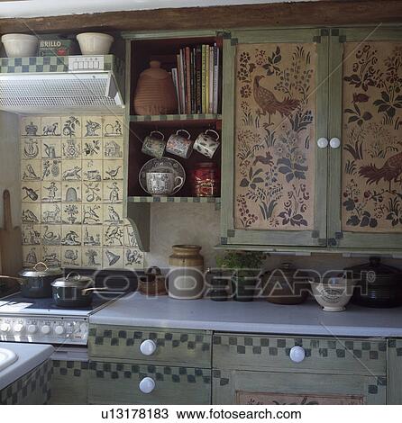 Flowers and birds painted on to cupboards in cottage kitchen with matching blue tiles above oven View Large Photo Image Stock Image - Flowers and birds painted on to cupboards in cottage kitchen with matching blue tiles above oven. Fotosearch