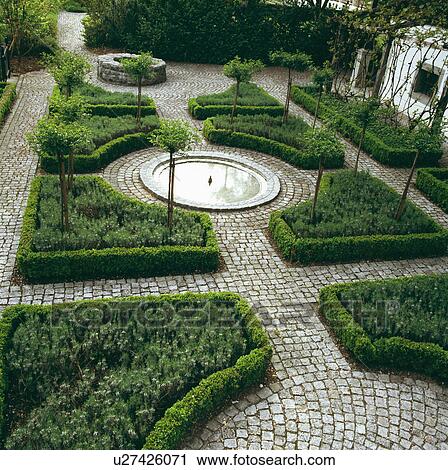 Stock Image - Formal knot garden with low box hedging and stone paving. Fotosearch