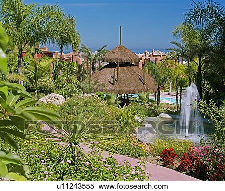 Fountain In Pond And Straw Gazebo In Gardens Of Spanish Holiday