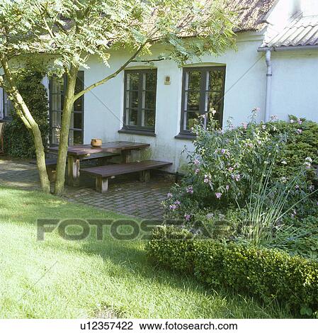 Stock Image - Furniture on patio in country garden in summer. Fotosearch