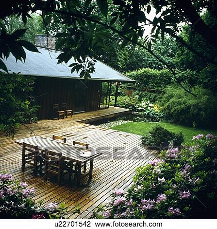 Stock Image - Furniture on patio in country garden in summer. Fotosearch