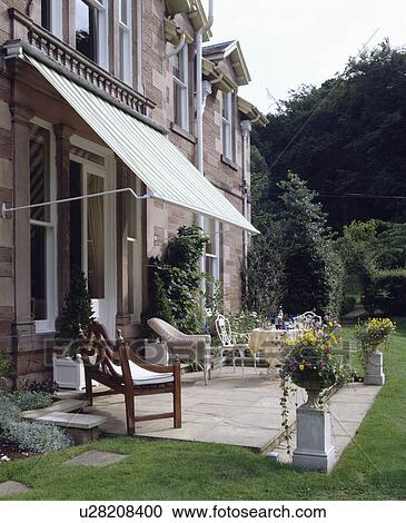 Stock Image - Furniture on patio in country garden in summer. Fotosearch