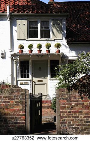 Gate open to white terraced cottage with shutters and plants in pots on porch above the front door View Large Photo Image Stock Image - Gate open to white terraced cottage with shutters and plants in pots on porch above the front door. Fotosearch