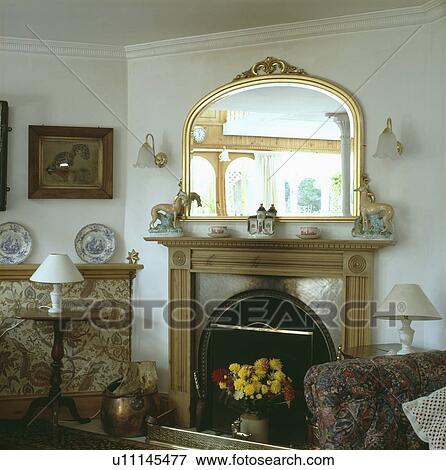 Gilt mirror above fireplace in traditional living room View Large Photo Image Stock Photo - Gilt mirror above fireplace in traditional living room. Fotosearch