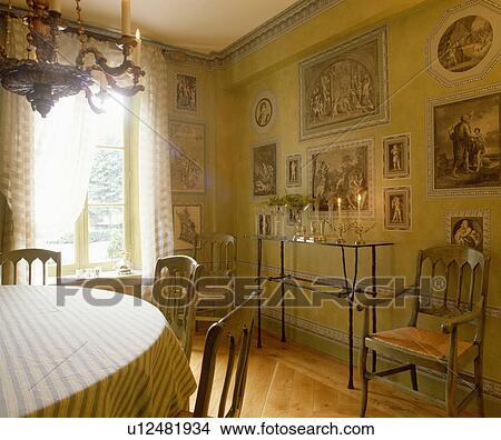 Picture - Glass and metal console table in dining room with collection of prints on the wall. Fotosearch