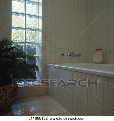 Stock Image - Glass brick window in modern cream tiled bathroom . Fotosearch