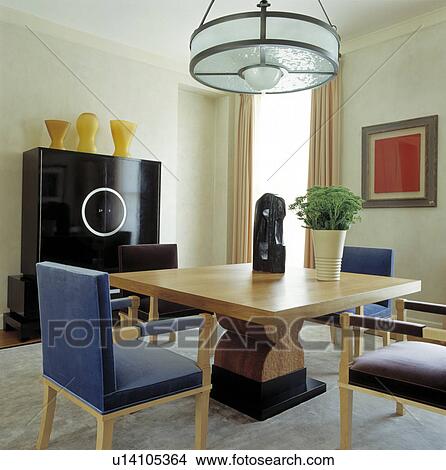 Glass light above pale wood table with sculpture in modern dining room with upholstered blue chairs and black cupboard View Large Photo Image Picture - Glass light above pale wood table with sculpture in modern dining room with upholstered blue chairs and black cupboard. Fotosearch