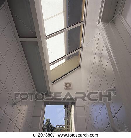 Stock Photo - Glass roof above shower in modern white tiled bathroom extension. Fotosearch