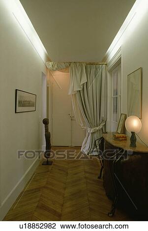 Globe lamp on console table and white curtain in narrow white hall with parquet floor and lighting on false ceiling View Large Photo Image Stock Image - Globe lamp on console table and white curtain in narrow white hall with parquet floor and lighting on false ceiling. Fotosearch