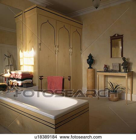 Gothic detail on tall fitted cupboards in neutral bathroom with panelled bath extending into the room View Large Photo Image Picture - Gothic detail on tall fitted cupboards in neutral bathroom with panelled bath extending into the room . Fotosearch
