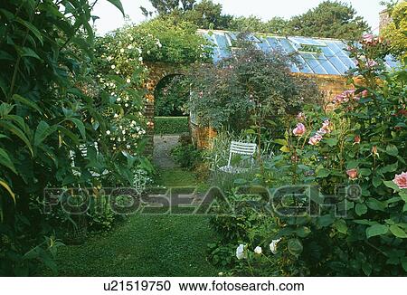 Stock Image - Grass path and rose borders in country garden in summer. Fotosearch