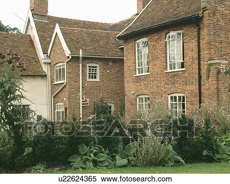 Stock Photography - Green garden border in front of detached traditional brick house. Fotosearch