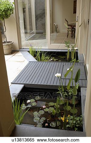 Grey decking bridge over angular pond in front of glass doors of modern Australian house View Large Photo Image Stock Photography - Grey decking bridge over angular pond in front of glass doors of modern Australian house . Fotosearch