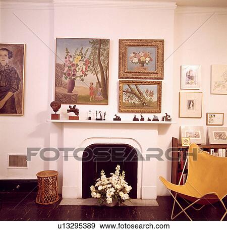 Group of pictures on wall above fireplace in living room with yellow butterfly chair View Large Photo Image Stock Photo - Group of pictures on wall above fireplace in living room with yellow butterfly chair. Fotosearch