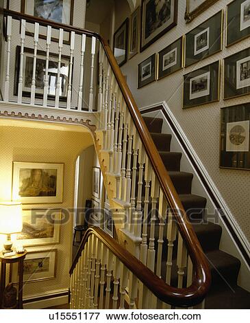 Group of pictures on wall above Victorian staircase with white bannisters and mahogany handrail View Large Photo Image Stock Photo - Group of pictures on wall above Victorian staircase with white bannisters and mahogany handrail. Fotosearch