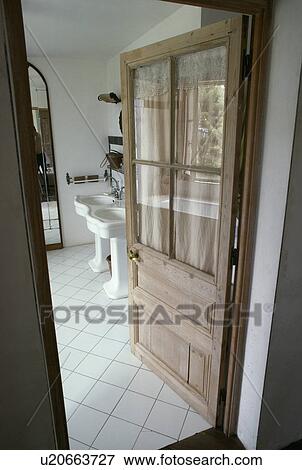 Half-glazed wooden door open to traditional white country bathroom View Large Photo Image Stock Photo - Half-glazed wooden door open to traditional white country bathroom . Fotosearch