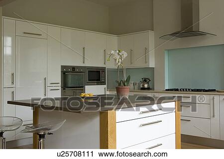 Stock Image - Island unit in modern white kitchen with turquoise wall. Fotosearch