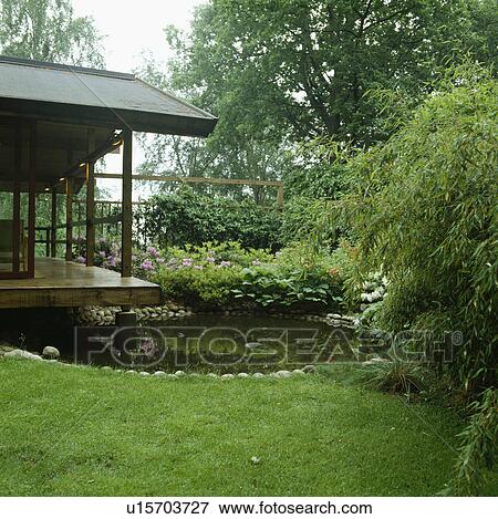 Japanese style covered veranda with round pebble edged pool Evergreen planting with bamboo View Large Photo Image Stock Photo - Japanese style covered veranda with round pebble edged pool Evergreen planting with bamboo. Fotosearch