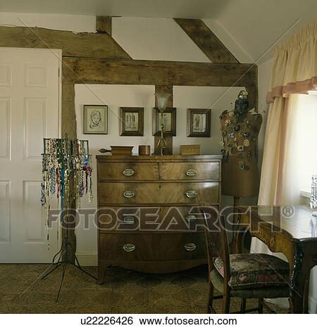 Jewellery displayed on stand and tailor's dummy inbeamed country bedroom with antique chest of drawers View Large Photo Image Stock Photograph - Jewellery displayed on stand and tailor's dummy inbeamed country bedroom with antique chest of drawers. Fotosearch