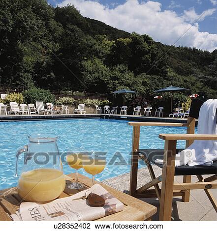 Jug of orange juice on table beside hotel swimming pool View Large Photo Image Stock Image - Jug of orange juice on table beside hotel swimming pool. Fotosearch