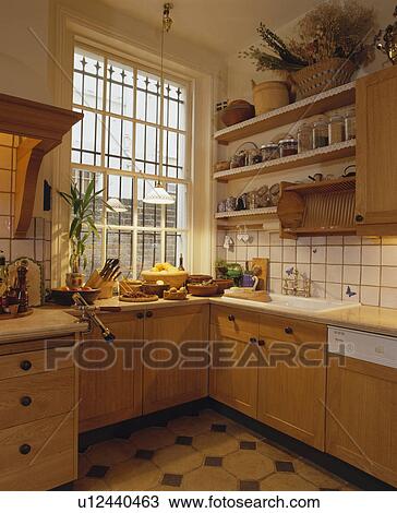 Stock Image - Kitchen with wooden units and shelves and security bars at the window. Fotosearch