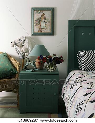 Lamp on small green cupboard beside bed View Large Photo Image Stock Photo - Lamp on small green cupboard beside bed . Fotosearch