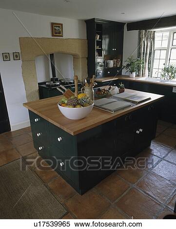 Large bowl of fruit and hob on island unit with drawers in country kitchen with terracotta tiled floor and black Aga oven View Large Photo Image Stock Photography - Large bowl of fruit and hob on island unit with drawers in country kitchen with terracotta tiled floor and black Aga oven. Fotosearch