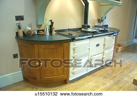 Stock Image - Large cream Aga in fitted kitchen unit with black granite worktop. Fotosearch