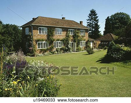Stock Image - Large lawn in front of traditional country house built in the fifties. Fotosearch