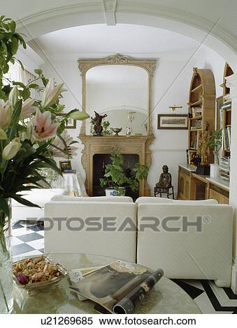 Stock Photography - Large mirror above fireplace in white living room with white sofa. Fotosearch