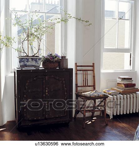 Stock Photograph - Large modern white bedroom with wooden floor boards, traditional style chest and cane chair . Fotosearch