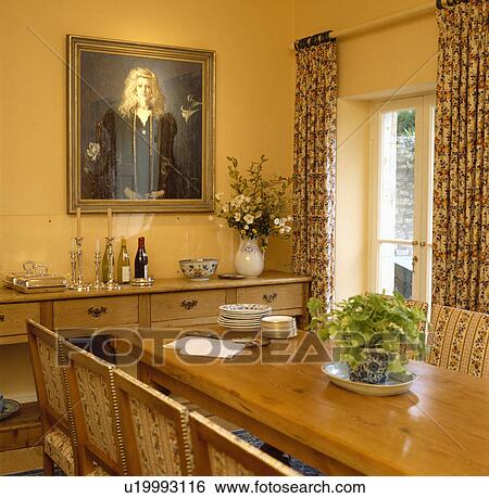 Large picture above pine sideboard in yellow dining room with patterned curtains and polished pine table View Large Photo Image Stock Photograph - Large picture above pine sideboard in yellow dining room with patterned curtains and polished pine table. Fotosearch
