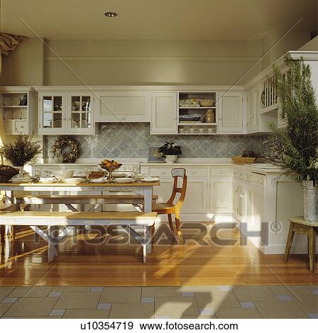 Stock Photo - Large traditional kitchen diningroom with painted table and bench and wooden floors.. Fotosearch