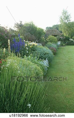 Stock Photograph - Lawn and herbaceous border in large country garden in summer. Fotosearch