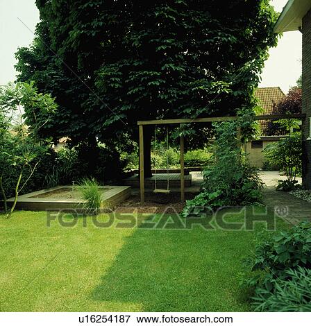 Stock Photo - Lawn in summer country garden with children's swing and sandpit. Fotosearch