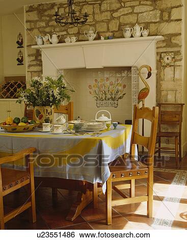 Leather and wood chairs in country dining room with yellow and blue cloth and white fireplace on stone wall View Large Photo Image Stock Photograph - Leather and wood chairs in country dining room with yellow and blue cloth and white fireplace on stone wall. Fotosearch