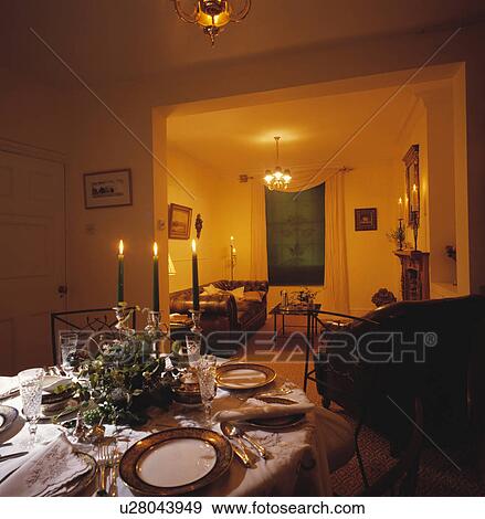 Lighted candles and place settings on table in traditional dining room with large doorway to living room View Large Photo Image Stock Photo - Lighted candles and place settings on table in traditional dining room with large doorway to living room. Fotosearch