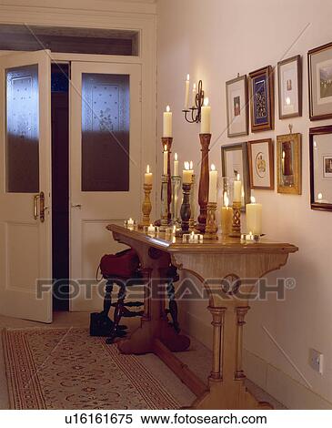Lighted candles in tall candlesticks on wooden console table in hall with engraved glass panels in double doors View Large Photo Image Stock Photography - Lighted candles in tall candlesticks on wooden console table in hall with engraved glass panels in double doors. Fotosearch