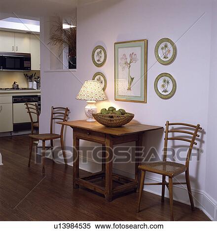 Lighted Lamp On Shaker Style Table And Wooden Chairs With Cane Seats In Openplan Hall With Wooden Flooring Stock Photography U13984535 Fotosearch