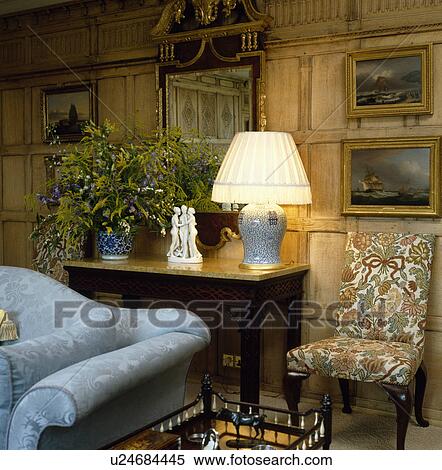 Lighted lamp on table in panelled living room with blue sofa View Large Photo Image Stock Photography - Lighted lamp on table in panelled living room with blue sofa. Fotosearch