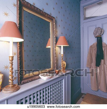 Lighted lamps on either side of carved wooden mirror on radiator in hall with star motif mauve wallpaper View Large Photo Image Stock Image - Lighted lamps on either side of carved wooden mirror on radiator in hall with star motif mauve wallpaper. Fotosearch