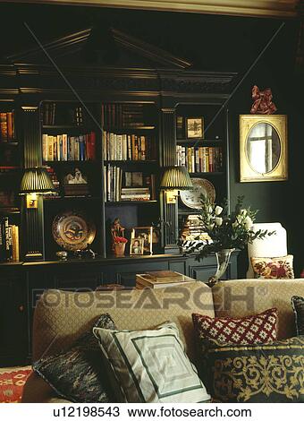 Stock Photo Of Lighted Lamps On Ed Bookshelves In Dark Green Stock Photo Lighted Lamps On Ed Bookshelves In Dark Green Living Room With Cushions Piled