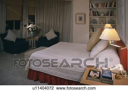 Lighted wall-lamp above bed with white textured bedcover in townhouse bedroom View Large Photo Image Stock Image - Lighted wall-lamp above bed with white textured bedcover in townhouse bedroom. Fotosearch