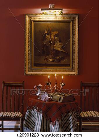 Stock Photo - Lighting above large picture above circular table with striped cloth in red dining room. Fotosearch