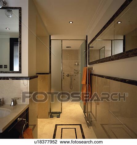Long mirror in travertine-tiled modern bathroom with opaque glass doors open to wet room shower View Large Photo Image Stock Image - Long mirror in travertine-tiled modern bathroom with opaque glass doors open to wet room shower. Fotosearch